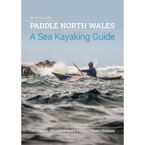 Book cover of 'Paddle North Wales: A Sea Kayaking Guide' with a sea kayaker in the water.
