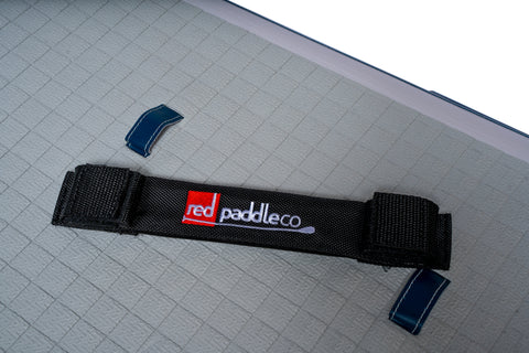 Close up image of a removable handle with Red Paddle Co embroidered into it. The background is showing the grid pattern of the deck of a paddleboard