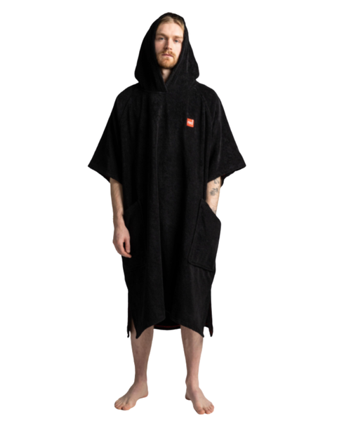 Person wearing a black hooded changing poncho with a red logo on a white background