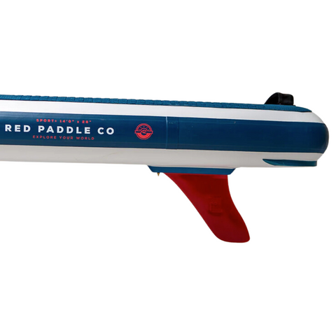 Side view of the tail section of a blue and white paddleboard with a fitted red fin. The board is white and blue and carries brand lettering  