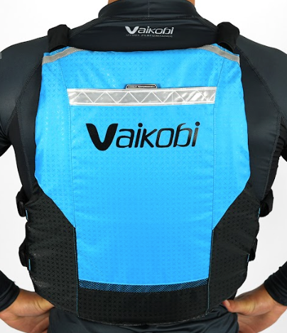 A person wearing a cyan and black Vaikobi V4 PFD Vest for Ocean Paddling. The vest is viewed from the back showing the logo and reflective detailing.