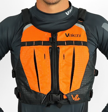 A person wearing an orange and black Vaikobi V4 PFD Vest for Ocean Paddling. The vest is visible over the person's long sleeve top, showcasing the front pockets.
