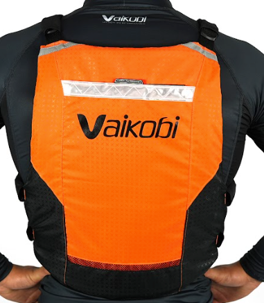 A person wearing an orange black Vaikobi V4 PFD Vest for Ocean Paddling. The vest is viewed from the back showing the logo and reflective detailing.