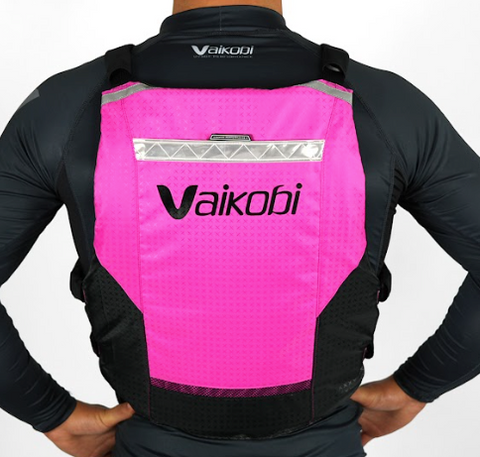 A person wearing a pink and black Vaikobi V4 PFD Vest for Ocean Paddling. The vest is viewed from the back showing the logo and reflective detailing.