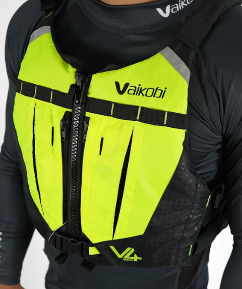 A person wearing a yellow and black Vaikobi V4 PFD Vest for Ocean Paddling. The vest is visible over the person's long sleeve top, showcasing the front pockets.