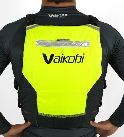 A person wearing a yellow and black Vaikobi V4 PFD Vest for Ocean Paddling. The vest is viewed from the back showing the logo and reflective detailing.