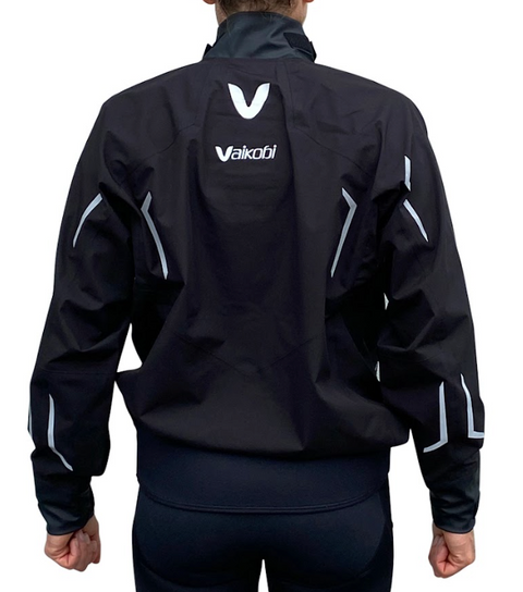A person wearing a black Vaikobi Performance paddling smock against a white background. The view of the subject is from the rear and includes reflective details and a Vaikobi logo