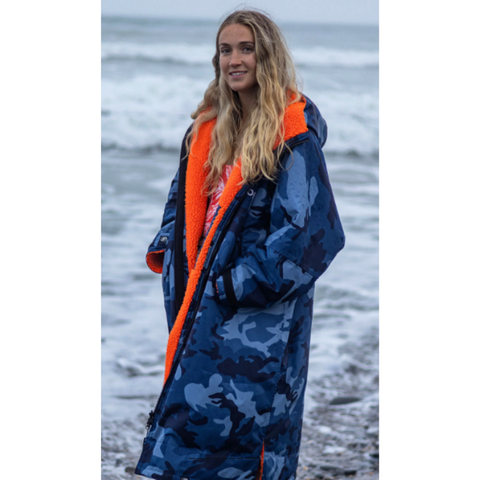 Person wearing a blue camouflage dryrobe with orange trim by the sea.