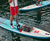 Paddleboarders standing on inflatable SUP's showing a deck bag as well as carbon paddles. 